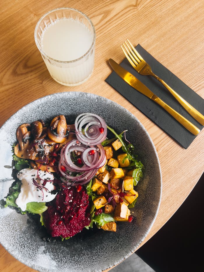 Healthy vegetarian bowl with mushrooms, beets, onions, and lemonade on a wooden table.
